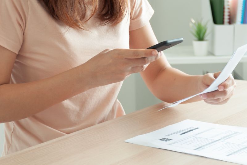 Person photographing a paper receipt with a smartphone to capture it for bookkeeping